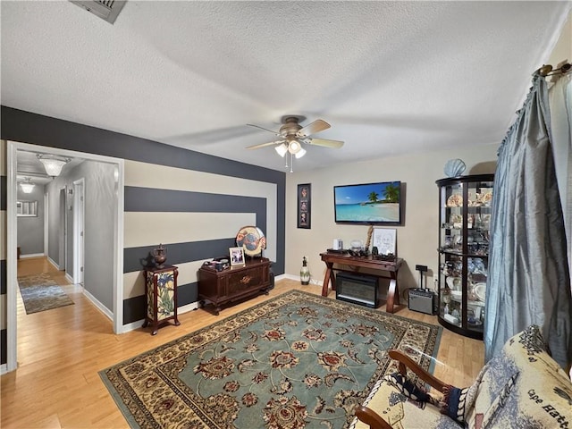 living room featuring ceiling fan, wood-type flooring, and a textured ceiling