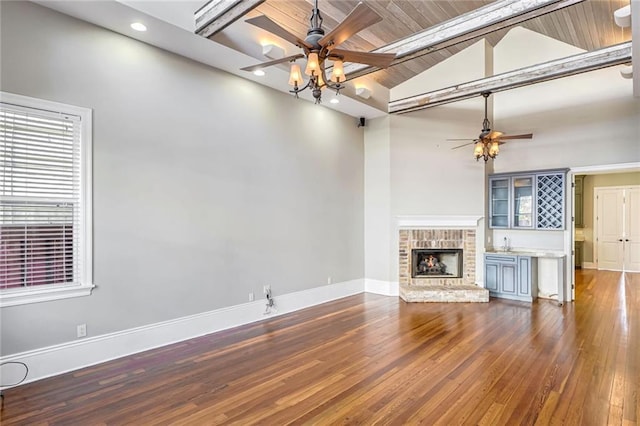 unfurnished living room with beam ceiling, hardwood / wood-style flooring, ceiling fan, wood ceiling, and a fireplace