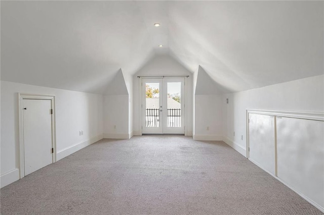 additional living space with light carpet, vaulted ceiling, and french doors