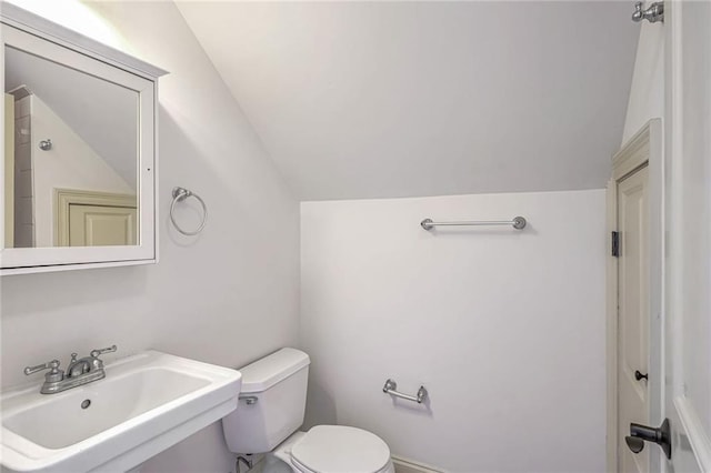 bathroom with sink, toilet, and lofted ceiling