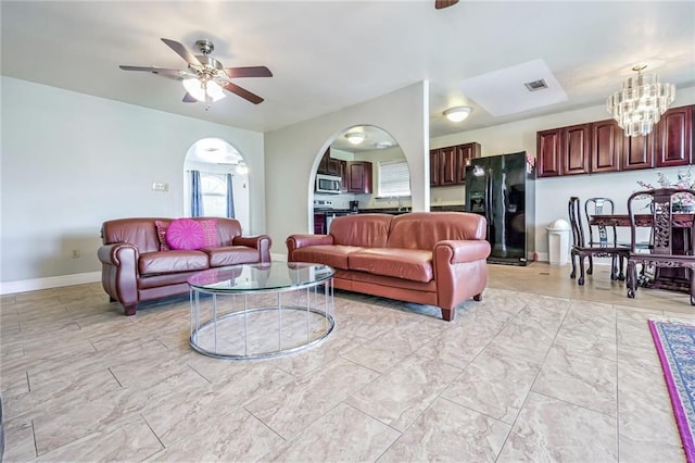 living room featuring sink and ceiling fan with notable chandelier