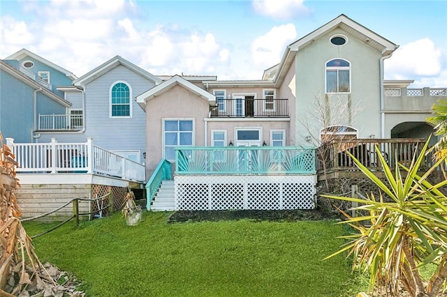 back of property with a yard, a wooden deck, and a balcony