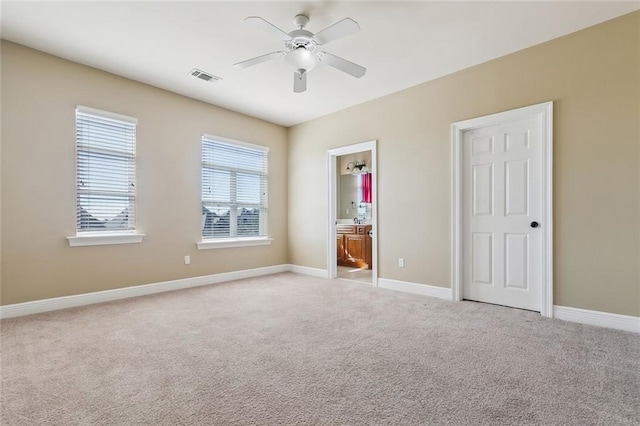 unfurnished bedroom featuring light carpet, ensuite bathroom, and ceiling fan