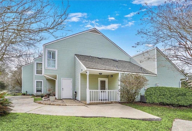 rear view of house with central AC unit, a yard, and a porch