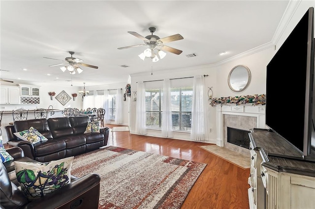 living room with dark hardwood / wood-style floors, ceiling fan, ornamental molding, and a fireplace