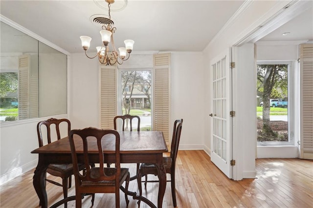 dining area with light wood-type flooring, plenty of natural light, and a chandelier