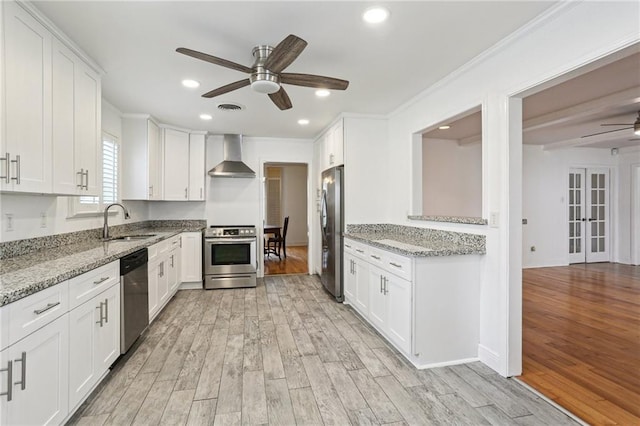 kitchen with sink, wall chimney exhaust hood, stainless steel appliances, and white cabinets