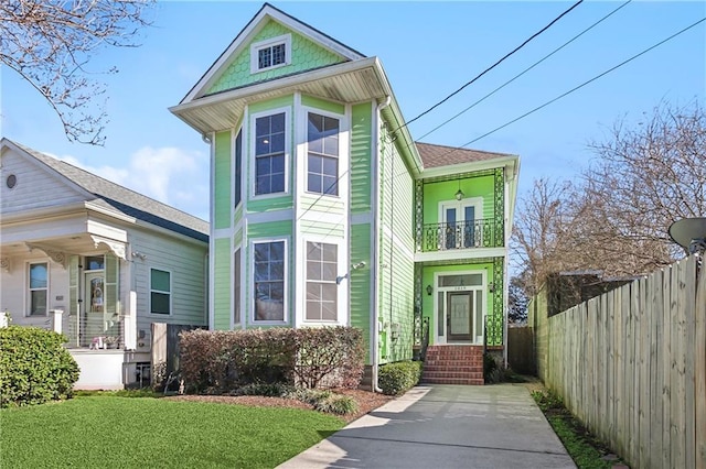 victorian house with a front yard and a balcony