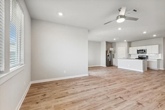 unfurnished living room with light hardwood / wood-style floors, sink, and ceiling fan