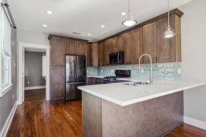 kitchen with decorative light fixtures, stainless steel appliances, dark wood-type flooring, kitchen peninsula, and a breakfast bar area