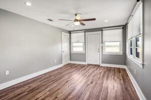 spare room featuring ceiling fan, a barn door, and hardwood / wood-style floors