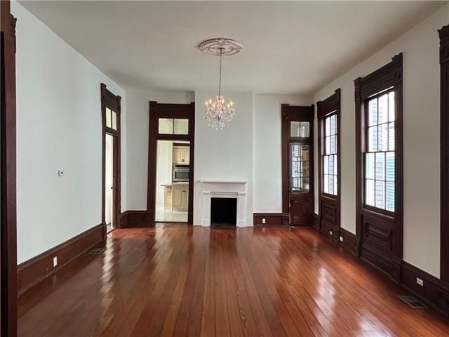 1608 Governor Nicholls St, New Orleans, LA 70116 - unfurnished living room with a chandelier, a fireplace, baseboards, and dark wood finished floors