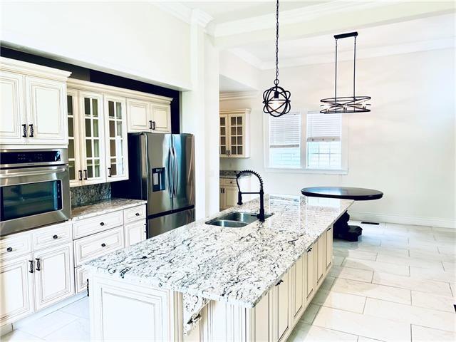 1608 Governor Nicholls St, New Orleans, LA 70116 - kitchen with crown molding, an island with sink, glass insert cabinets, appliances with stainless steel finishes, and a sink