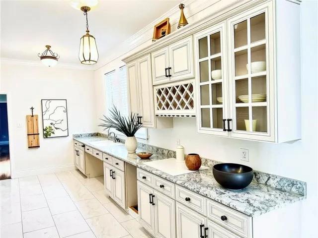 1608 Governor Nicholls St, New Orleans, LA 70116 - bar with hanging light fixtures, baseboards, a sink, crown molding, and marble finish floor