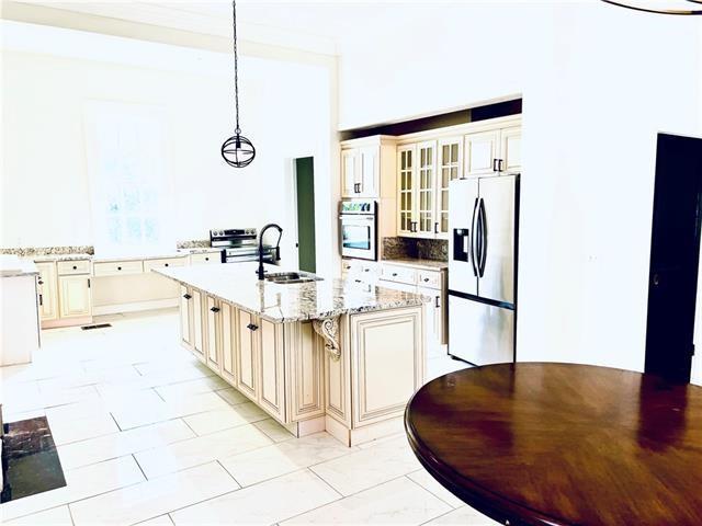 1608 Governor Nicholls St, New Orleans, LA 70116 - kitchen featuring cream cabinetry, a sink, glass insert cabinets, and stainless steel appliances