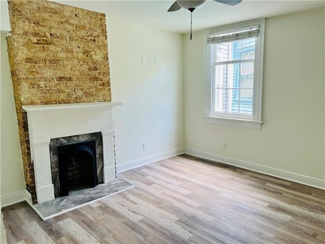 1608 Governor Nicholls St, New Orleans, LA 70116 - unfurnished living room featuring baseboards, a ceiling fan, wood finished floors, and a fireplace
