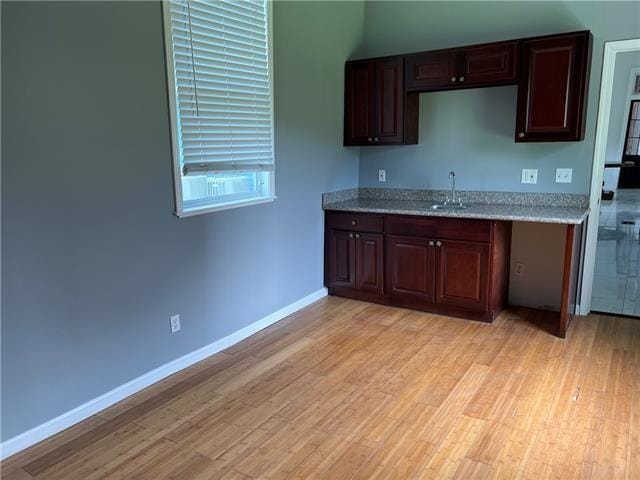 1608 Governor Nicholls St, New Orleans, LA 70116 - kitchen with dark brown cabinetry, baseboards, light wood-type flooring, light stone counters, and a sink