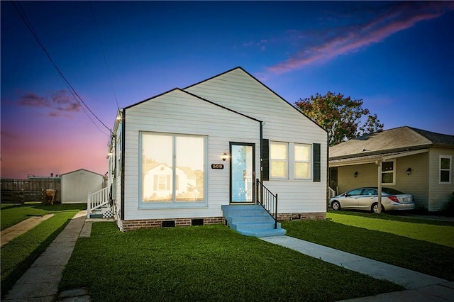 bungalow-style house with entry steps, crawl space, fence, and a lawn