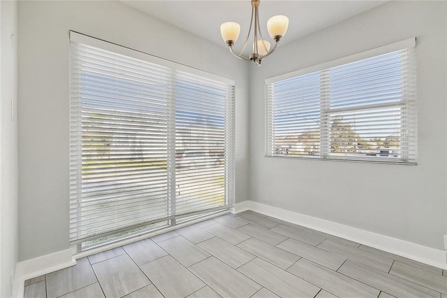 empty room with baseboards and a chandelier