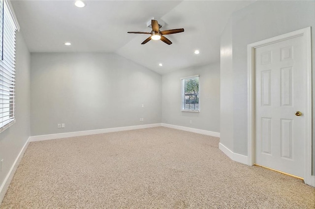 spare room featuring lofted ceiling, recessed lighting, light colored carpet, and baseboards