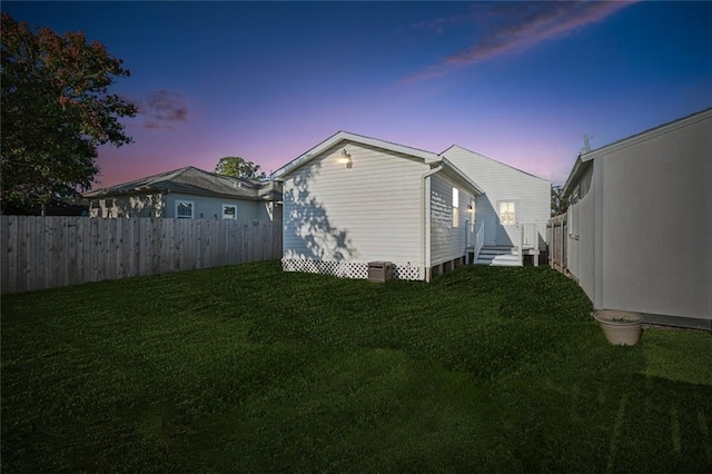 property exterior at dusk with fence and a lawn