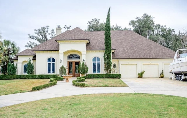 view of front of property featuring a front yard, french doors, and a garage