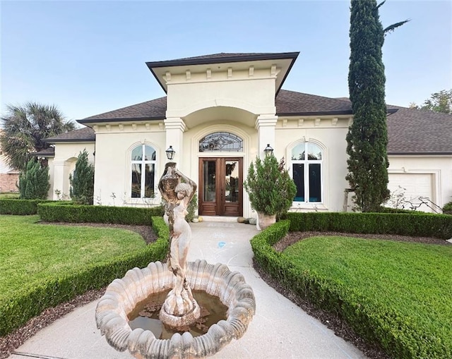 view of front of home featuring stucco siding, roof with shingles, a front lawn, and french doors