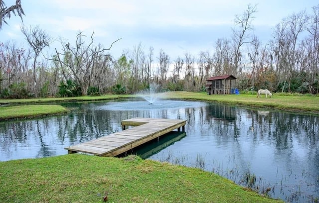 view of dock with a yard and a water view