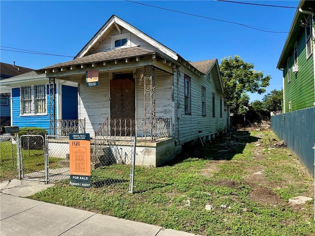 shotgun-style home featuring a fenced front yard, a porch, and a gate