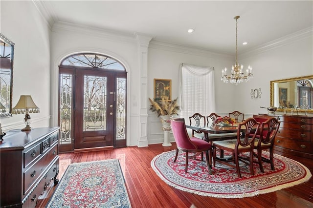 entryway featuring hardwood / wood-style flooring, ornamental molding, and a chandelier