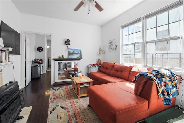 living room with heating unit, dark hardwood / wood-style flooring, and ceiling fan