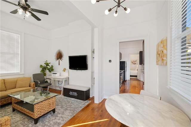 living room with ceiling fan with notable chandelier and hardwood / wood-style floors