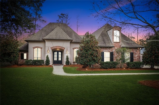 french provincial home featuring a yard and french doors