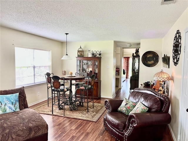 living area featuring wood finished floors, a textured ceiling, and baseboards