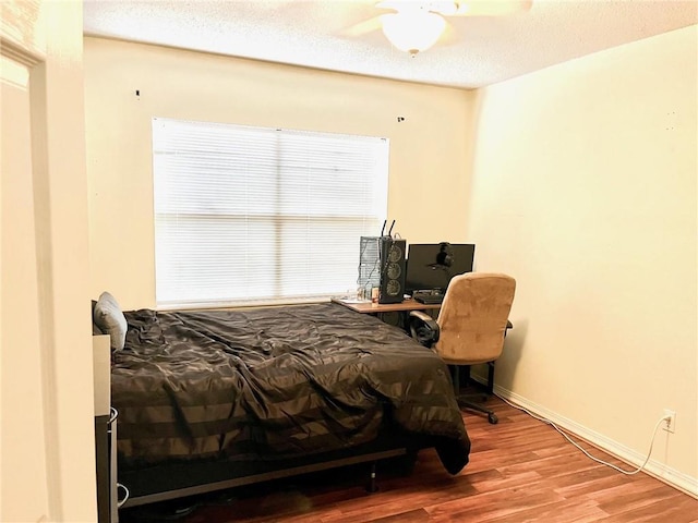 bedroom featuring wood finished floors, baseboards, and a textured ceiling