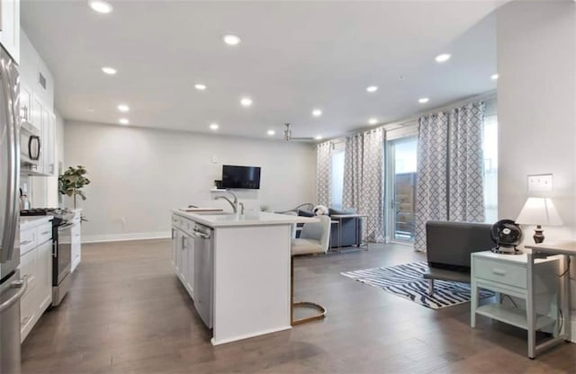 kitchen featuring appliances with stainless steel finishes, white cabinets, a kitchen island with sink, and a kitchen breakfast bar