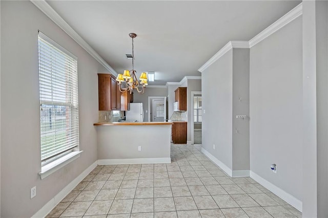 kitchen featuring kitchen peninsula, white refrigerator, an inviting chandelier, ornamental molding, and backsplash