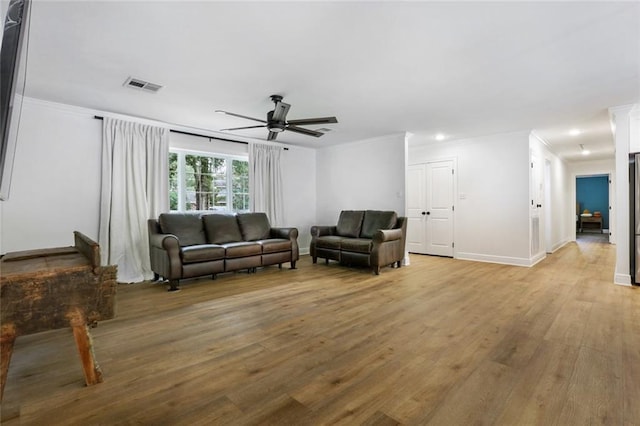 living room featuring hardwood / wood-style floors, ceiling fan, and ornamental molding