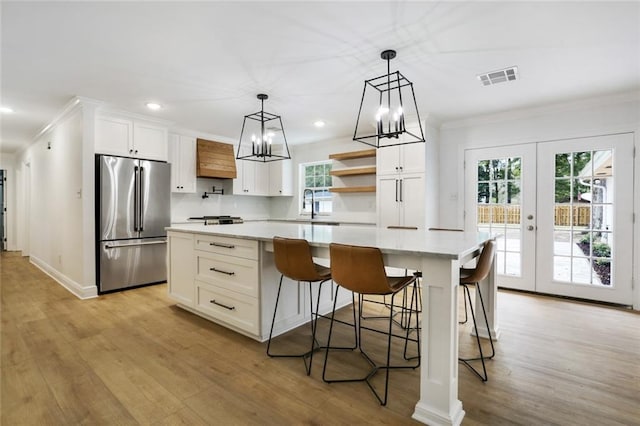 kitchen featuring sink, a center island, white cabinetry, decorative light fixtures, and stainless steel fridge