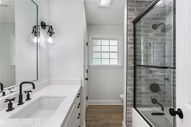 full bathroom featuring toilet, vanity, shower / bath combination with glass door, and wood-type flooring