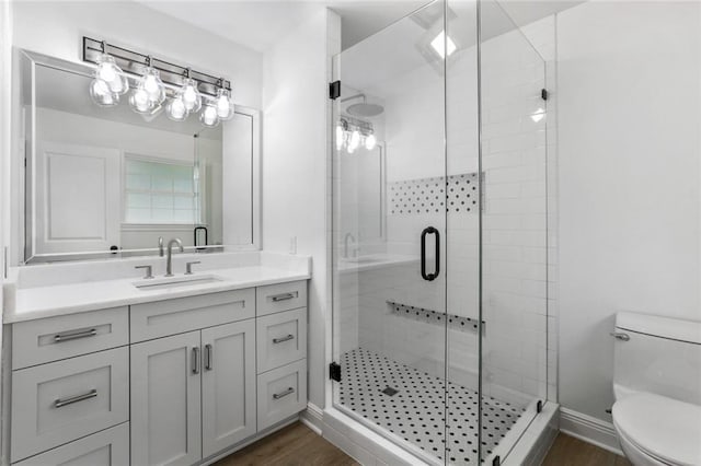 bathroom featuring toilet, vanity, hardwood / wood-style floors, and an enclosed shower