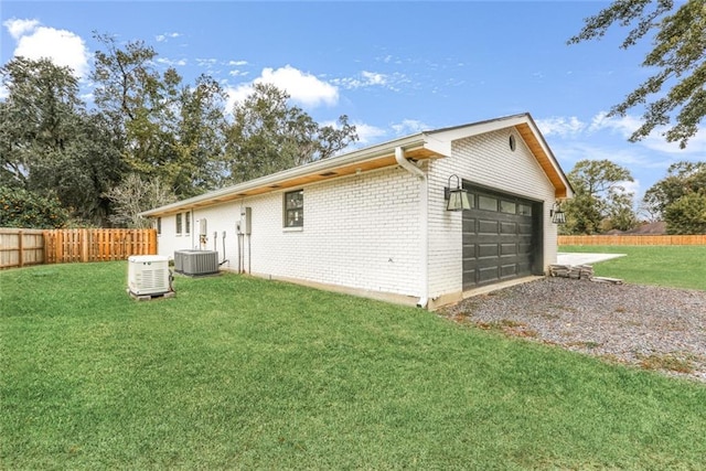 back of property featuring central AC unit, a yard, and a garage