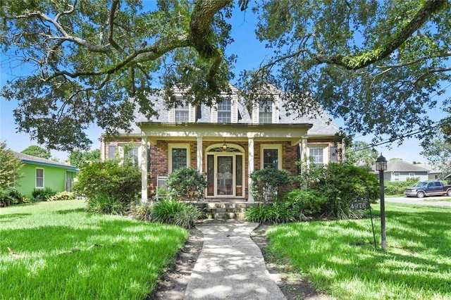 cape cod-style house with a porch, a front yard, and brick siding