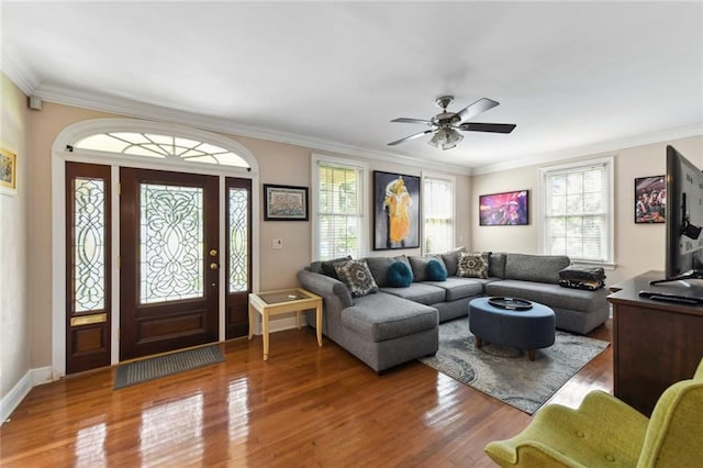 living area with ornamental molding, wood finished floors, and a ceiling fan