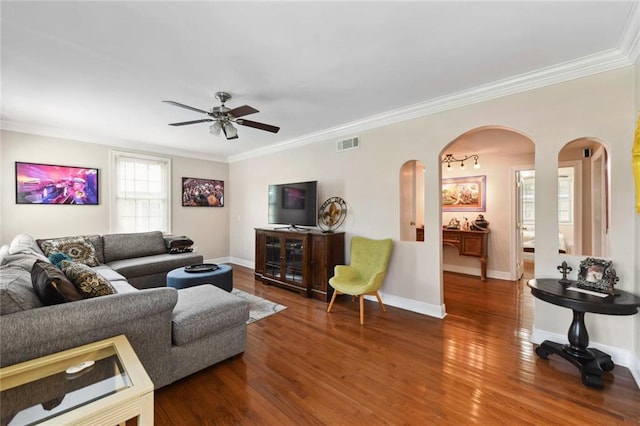 living area with arched walkways, wood finished floors, visible vents, and crown molding