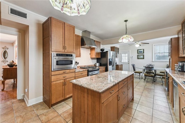 kitchen with visible vents, wall chimney exhaust hood, a kitchen island, appliances with stainless steel finishes, and light stone counters