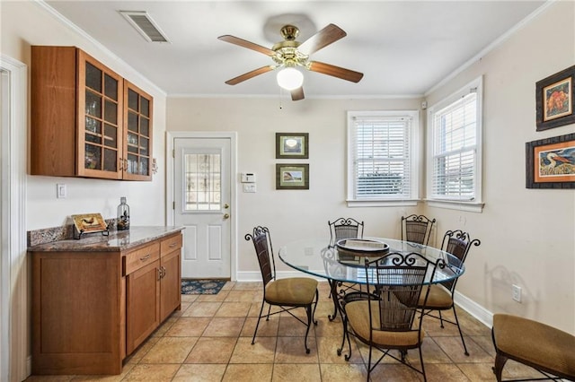 dining area featuring baseboards, a ceiling fan, visible vents, and crown molding