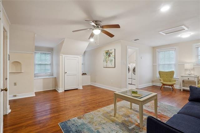 living area featuring ceiling fan, wood finished floors, baseboards, washer and dryer, and attic access