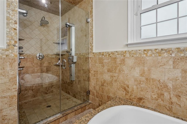 full bath featuring a wainscoted wall, a shower stall, a washtub, and tile walls