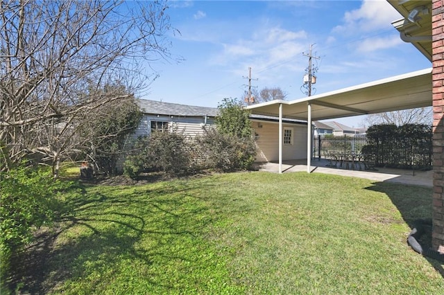 view of yard with a carport, a patio area, and fence